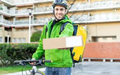 Young,Courier,With,Bicycle,Delivering,Box,To,The,Customer,-