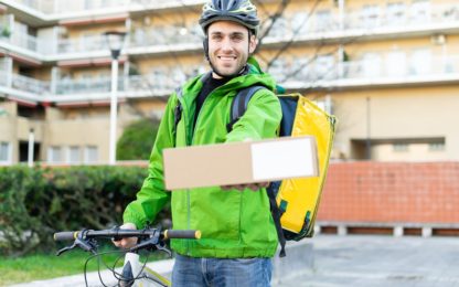 Young,Courier,With,Bicycle,Delivering,Box,To,The,Customer,-